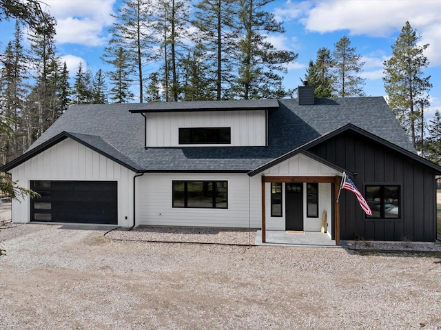 modern farmhouse style home with an attached garage, a shingled roof, board and batten siding, a chimney, and driveway