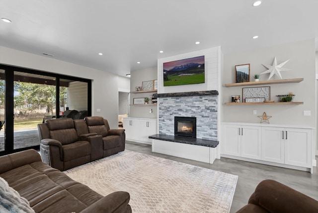 living room featuring a glass covered fireplace, recessed lighting, and concrete floors