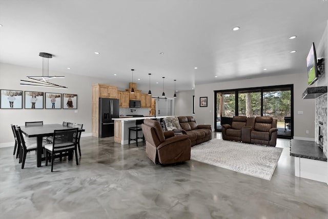 living room featuring recessed lighting, baseboards, concrete flooring, and a stone fireplace