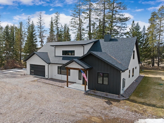 modern farmhouse with board and batten siding, a shingled roof, a chimney, a garage, and driveway