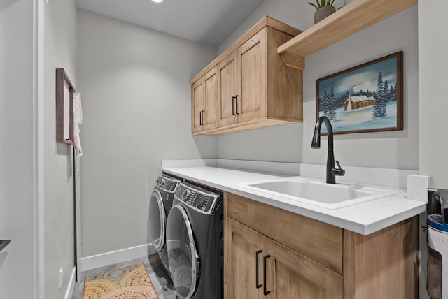 washroom with a sink, baseboards, cabinet space, and washer and dryer