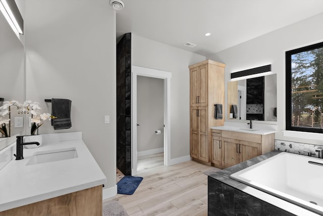 bathroom with two vanities, a bath, visible vents, and a sink