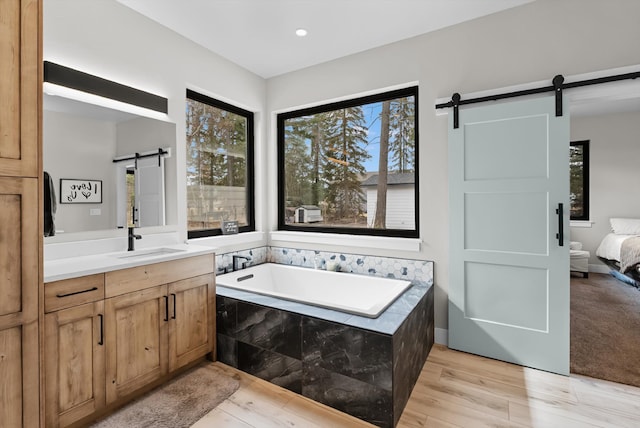 full bath with vanity, a garden tub, recessed lighting, wood finished floors, and ensuite bath