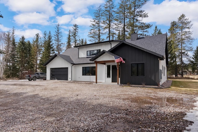 modern farmhouse with driveway, a chimney, an attached garage, and a shingled roof