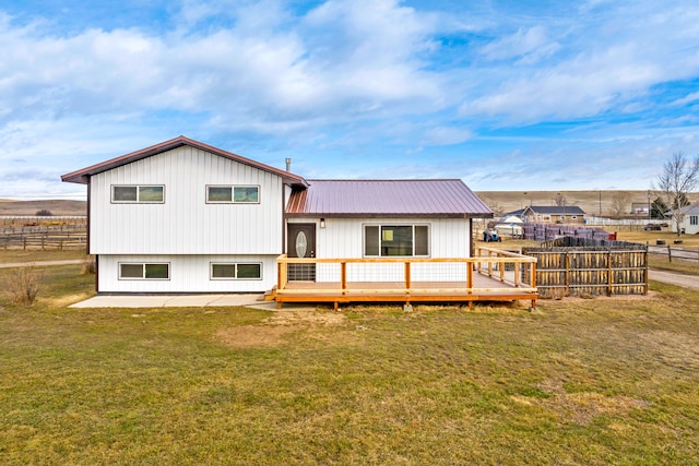 rear view of property with a deck, metal roof, a yard, and fence