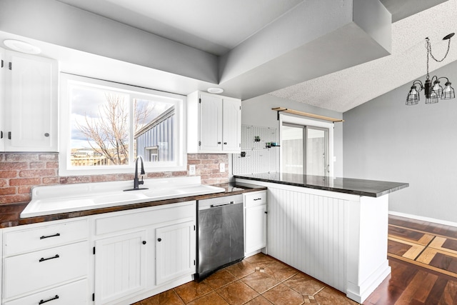 kitchen featuring backsplash, dark countertops, a peninsula, white cabinets, and dishwasher