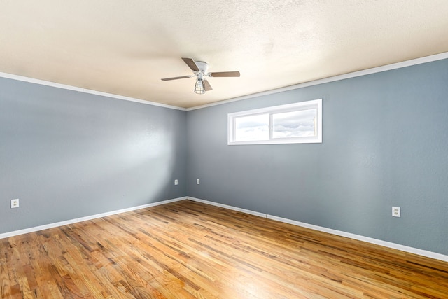 spare room featuring a textured ceiling, crown molding, baseboards, and wood finished floors