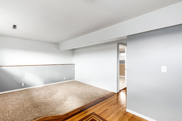 spare room with baseboards and wood finished floors