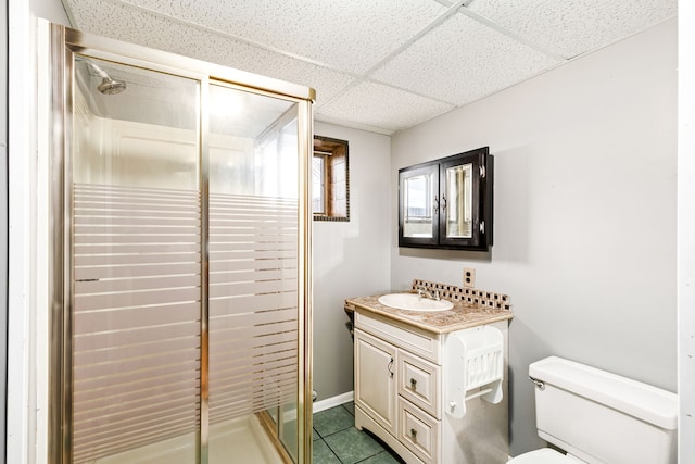 bathroom featuring a drop ceiling, vanity, toilet, and a shower stall