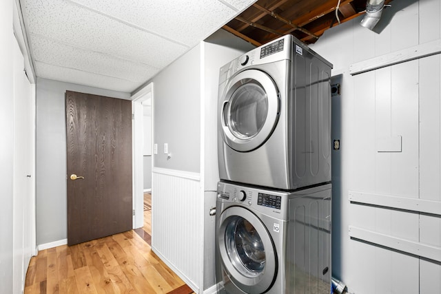 clothes washing area featuring wood finished floors, laundry area, and stacked washer / dryer