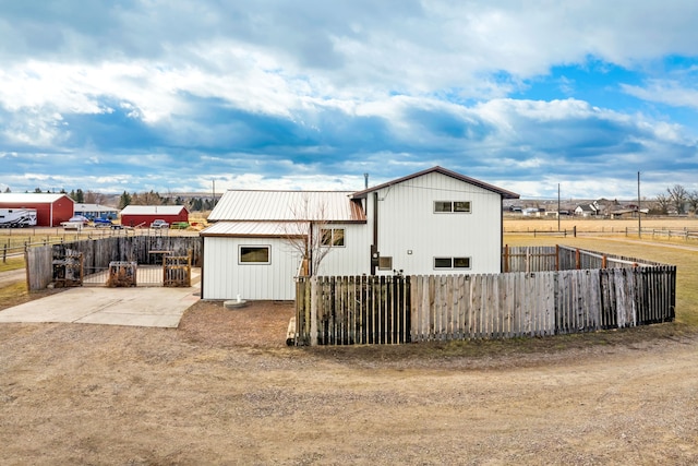 back of property with a fenced front yard and metal roof