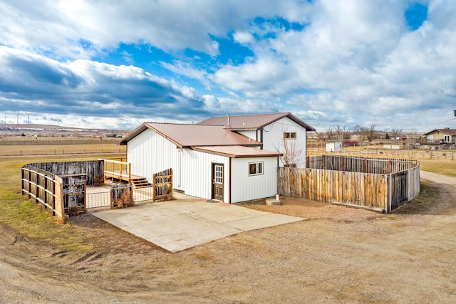 exterior space with a patio area, metal roof, an outbuilding, and fence