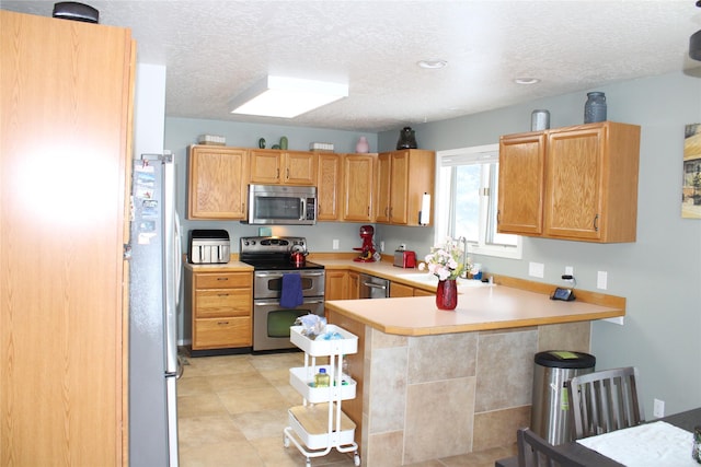 3004 Green Cir, Butte, MT 59701 - kitchen featuring stainless steel appliances, a peninsula, light countertops, a kitchen breakfast bar, and a textured ceiling