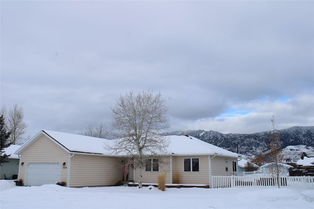 view of front facade featuring a garage, a mountain view, and fence