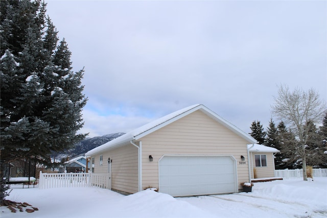 view of snow covered exterior with fence and a garage