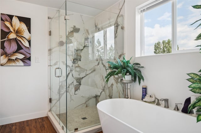 full bath featuring a marble finish shower, a freestanding tub, plenty of natural light, and wood finished floors