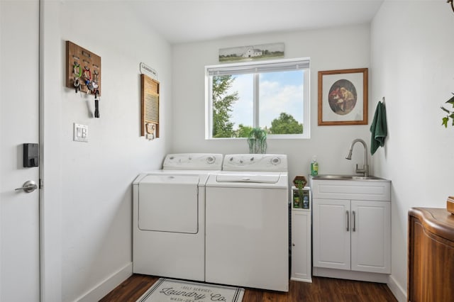 clothes washing area with a sink, baseboards, washing machine and dryer, cabinet space, and dark wood-style flooring