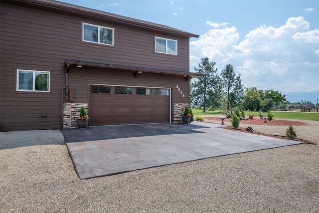 view of home's exterior with stone siding, driveway, and an attached garage