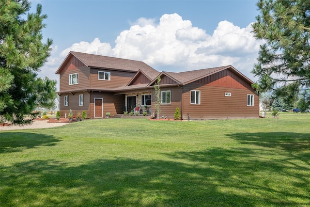 rear view of property with board and batten siding, a shingled roof, and a yard