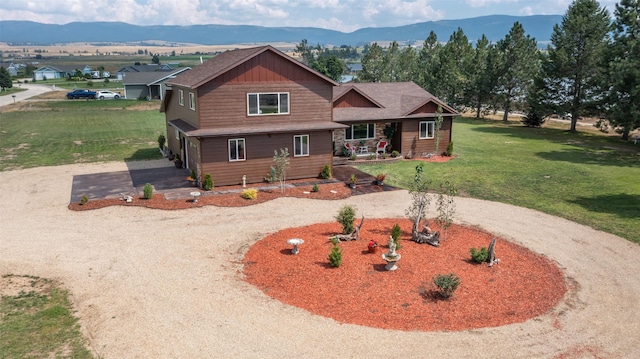 view of front of home featuring a mountain view, a front lawn, and dirt driveway