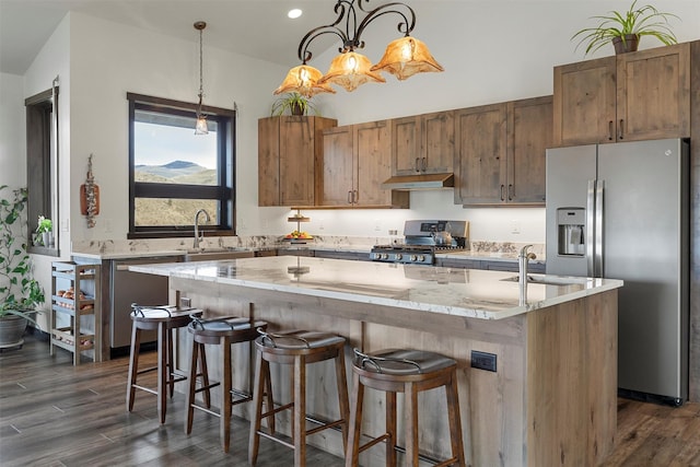 kitchen with under cabinet range hood, a center island, appliances with stainless steel finishes, and a sink