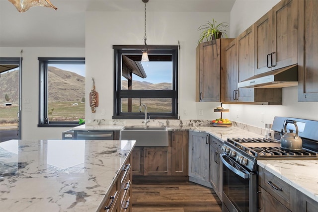 kitchen featuring light stone counters, dark wood-style floors, stainless steel gas range, a sink, and under cabinet range hood