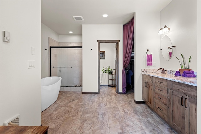 bathroom with vanity, a shower stall, a soaking tub, and visible vents