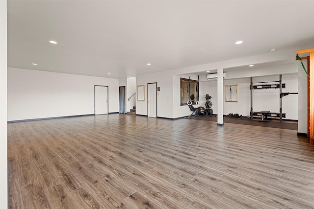 exercise room with recessed lighting, wood finished floors, baseboards, and a wall mounted air conditioner