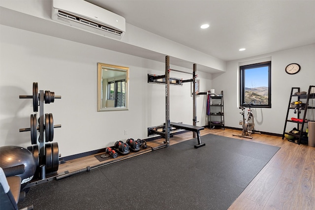 workout room featuring recessed lighting, baseboards, wood finished floors, and a wall unit AC