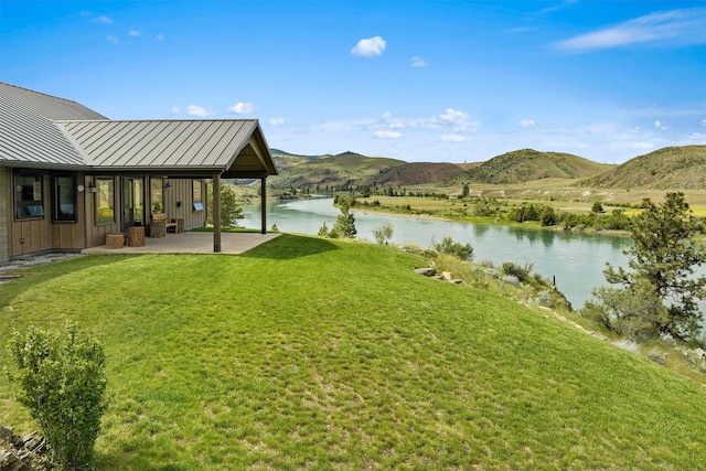 view of yard featuring a water and mountain view and a patio