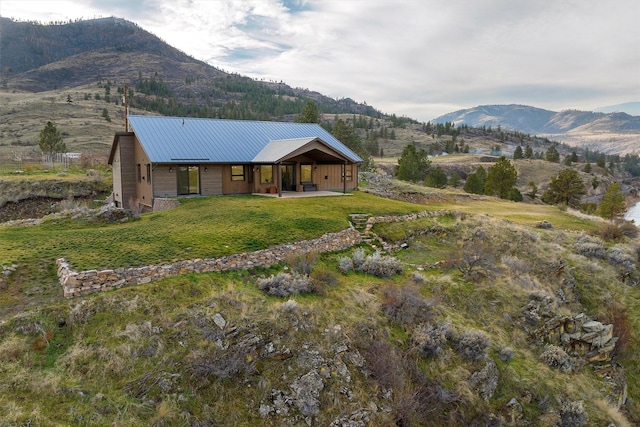 exterior space with a front yard, a mountain view, and metal roof