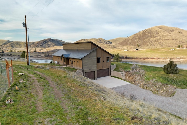 view of front of property with a water and mountain view, driveway, and a garage