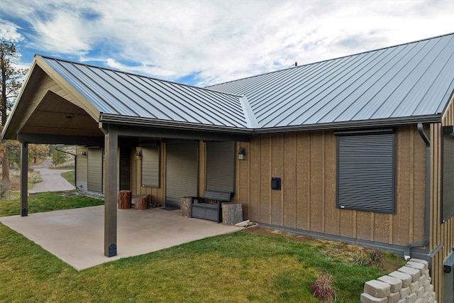 rear view of house with a yard, a standing seam roof, metal roof, and a patio