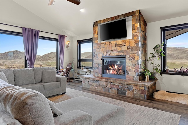 living area with ceiling fan, lofted ceiling, wood finished floors, and a fireplace