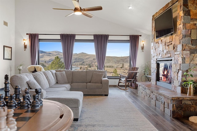 living area featuring visible vents, high vaulted ceiling, wood finished floors, a stone fireplace, and ceiling fan