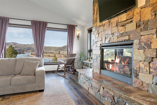 living room with a fireplace, vaulted ceiling, wood finished floors, and a mountain view