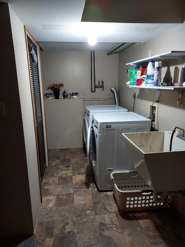 laundry room featuring laundry area, stone finish flooring, separate washer and dryer, and a sink