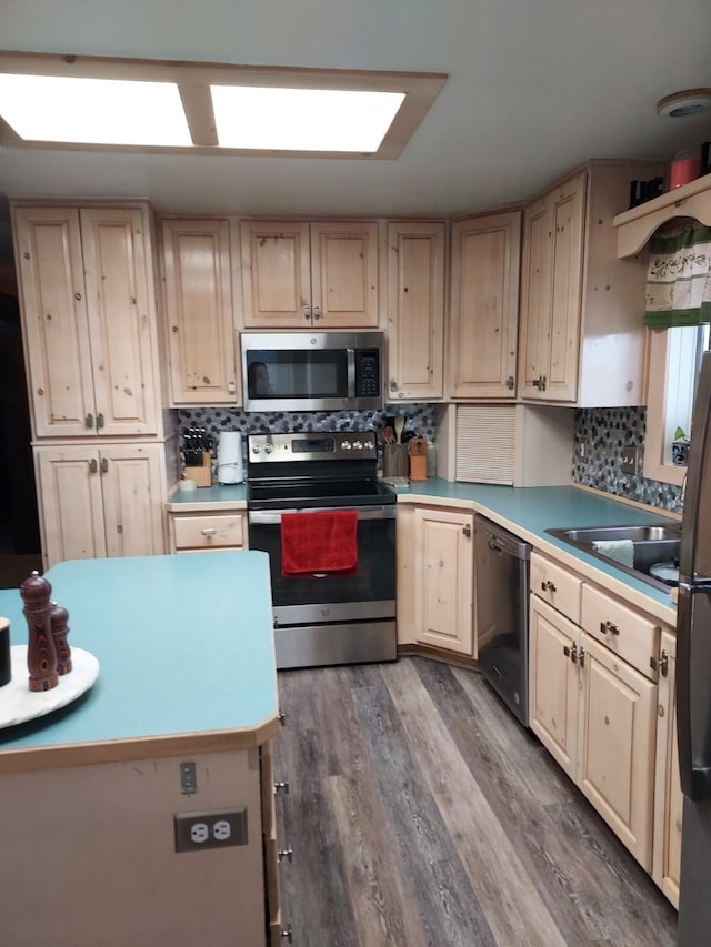 kitchen featuring light countertops, backsplash, wood finished floors, and appliances with stainless steel finishes