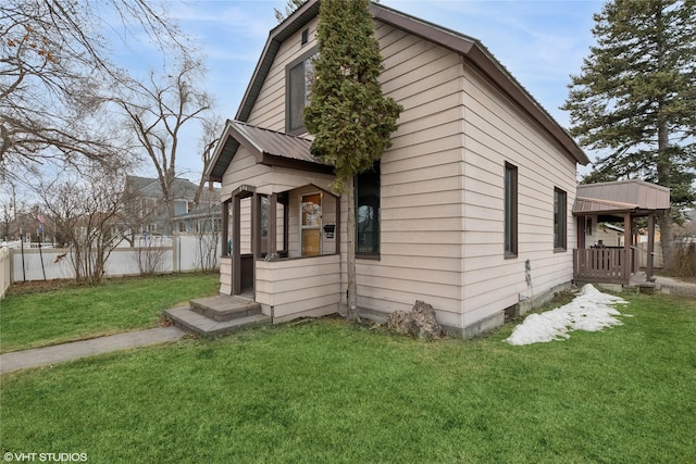 view of front of house with metal roof, a front lawn, and fence