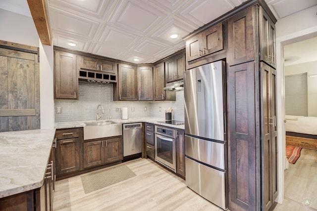 kitchen featuring an ornate ceiling, a sink, decorative backsplash, stainless steel appliances, and under cabinet range hood