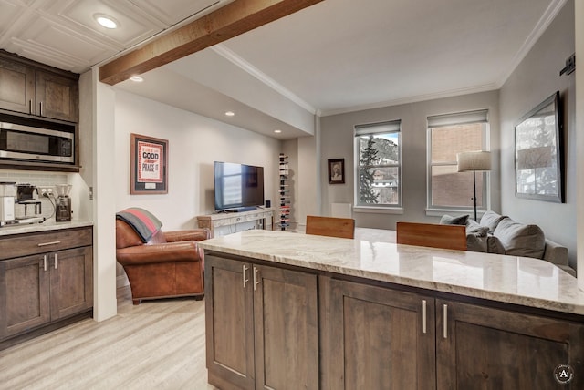 kitchen featuring light stone counters, stainless steel microwave, dark brown cabinets, and open floor plan