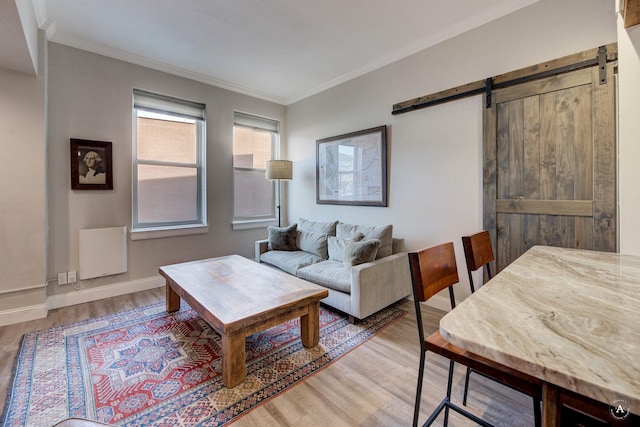 living area with light wood-style floors, a barn door, and ornamental molding