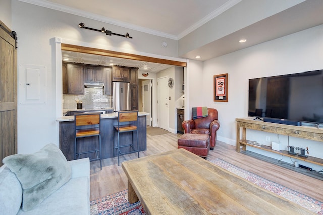 living room with baseboards, light wood-type flooring, a barn door, ornamental molding, and electric panel