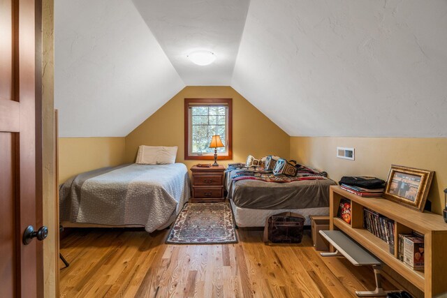 bedroom with vaulted ceiling and wood finished floors