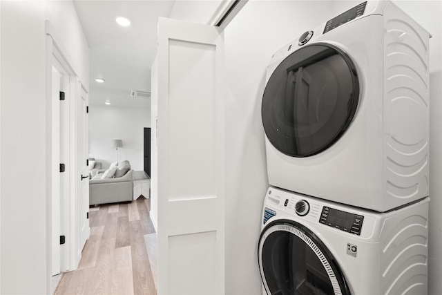 clothes washing area featuring recessed lighting, stacked washer / drying machine, laundry area, and light wood finished floors