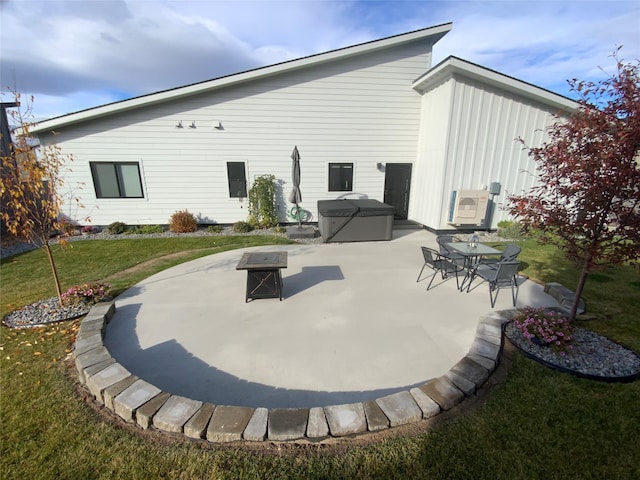 rear view of property featuring a lawn, a hot tub, and a patio