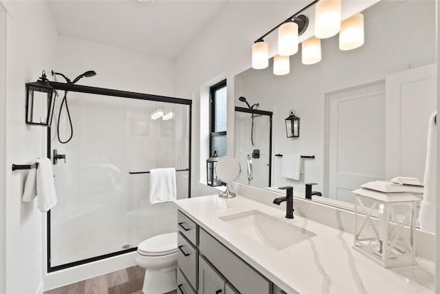 full bathroom with vanity, a shower stall, toilet, and wood finished floors