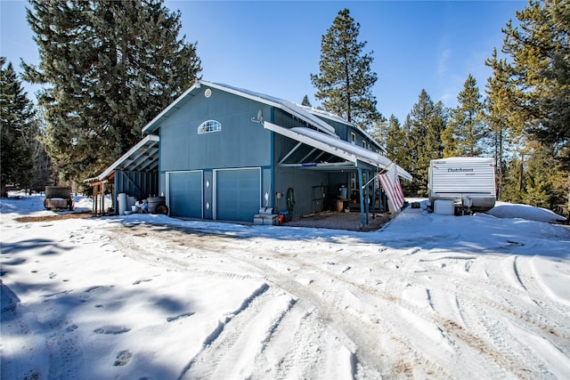 snow covered structure featuring an outdoor structure and an outbuilding