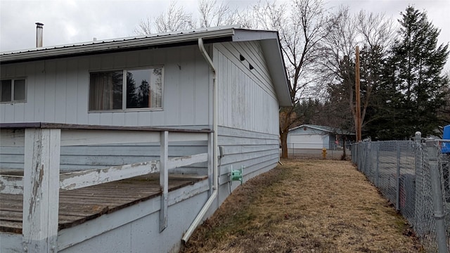 view of side of property with metal roof and fence