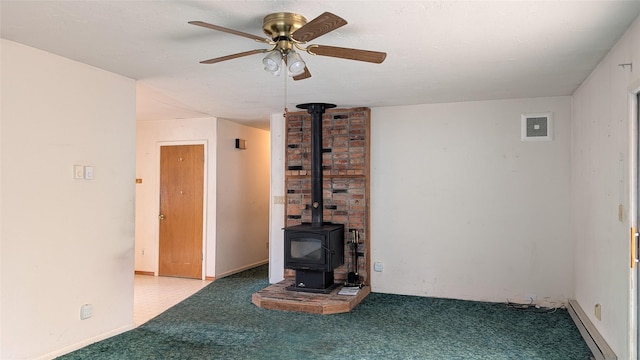 unfurnished living room with a baseboard radiator, carpet floors, a ceiling fan, and a wood stove